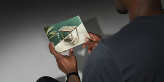 Person holding a gift voucher with a green cover.