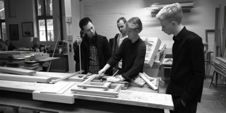Group of people in a workshop setting with tools and materials on tables.